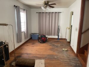 A room with worn hardwood floors before renovation, showing the initial state for NV Floors LLC in Pittsburgh, PA.