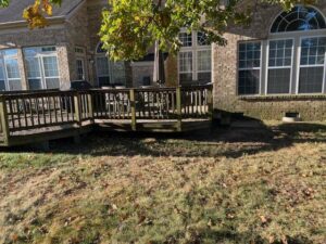 A worn wooden deck attached to a brick house, ready for repair or maintenance by Castano Design Build in Charlotte, NC.