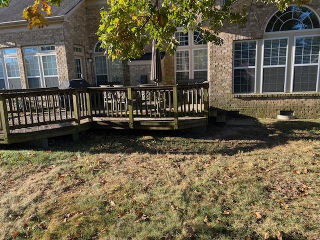 A worn wooden deck attached to a brick house, ready for repair or maintenance by Castano Design Build in Charlotte, NC.