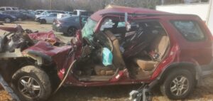 A completely wrecked red SUV, seen from the side, awaiting junk car removal by Don's Automotive Removal in Thomasville, NC.