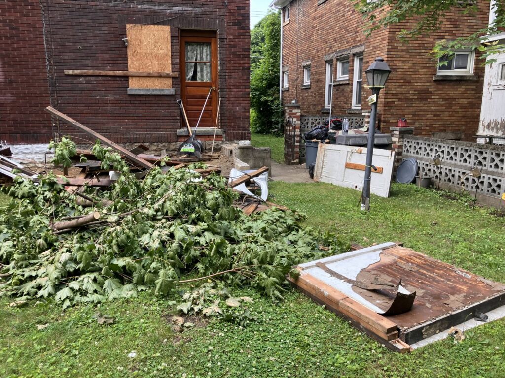 A large pile of tree branches, wood debris, and other junk in a backyard, ready for removal by HaulPros in Erie, PA.