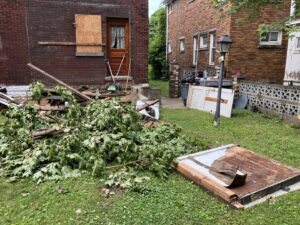 A large pile of tree branches, wood debris, and other junk in a backyard, ready for removal by HaulPros in Erie, PA.