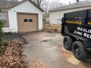 A Strong Lion Junk Removal trailer parked in a driveway, ready for yard waste and leaf removal services in Fayetteville, AR.