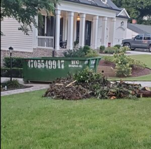 A large pile of yard waste and branches next to an IEG Disposal roll-off dumpster for removal in Canton, GA.