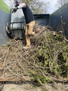 A Junk It OR Dump It worker in Independence, MO, loading yard waste and branches into a junk removal truck.