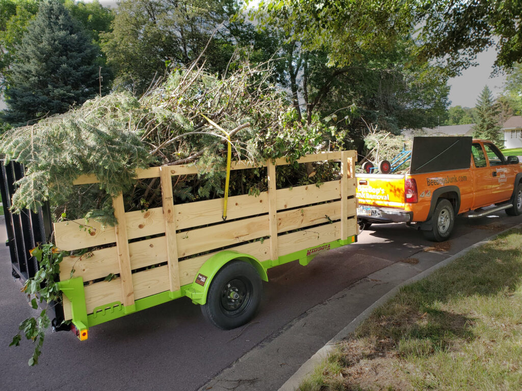 A BeeBop's Junk Removal truck pulling a trailer full of yard waste and tree branches in Sioux Falls, SD.