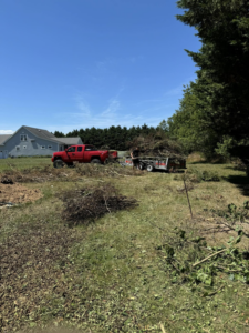 A red truck and trailer loaded with yard waste during a junk removal service by DJ's Hauling & Junk Removal Services in Georgetown, DE.