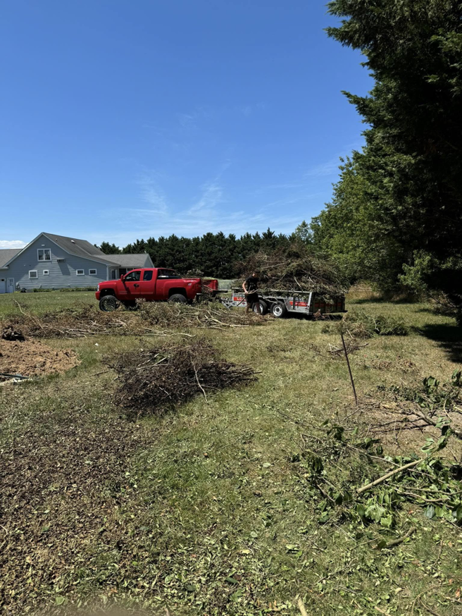 A red truck and trailer loaded with yard waste during a junk removal service by DJ's Hauling & Junk Removal Services in Georgetown, DE.
