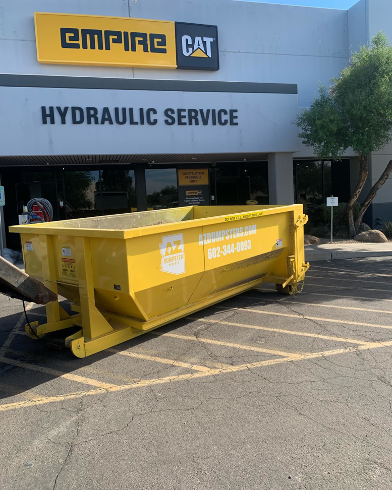 A yellow dumpster placed in a commercial parking lot by AZ Dumpster Rentals for junk removal in Surprise, AZ