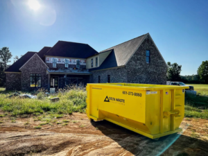 A yellow Delta Waste Solutions dumpster on a construction site in Hattiesburg, MS, ready for junk removal.