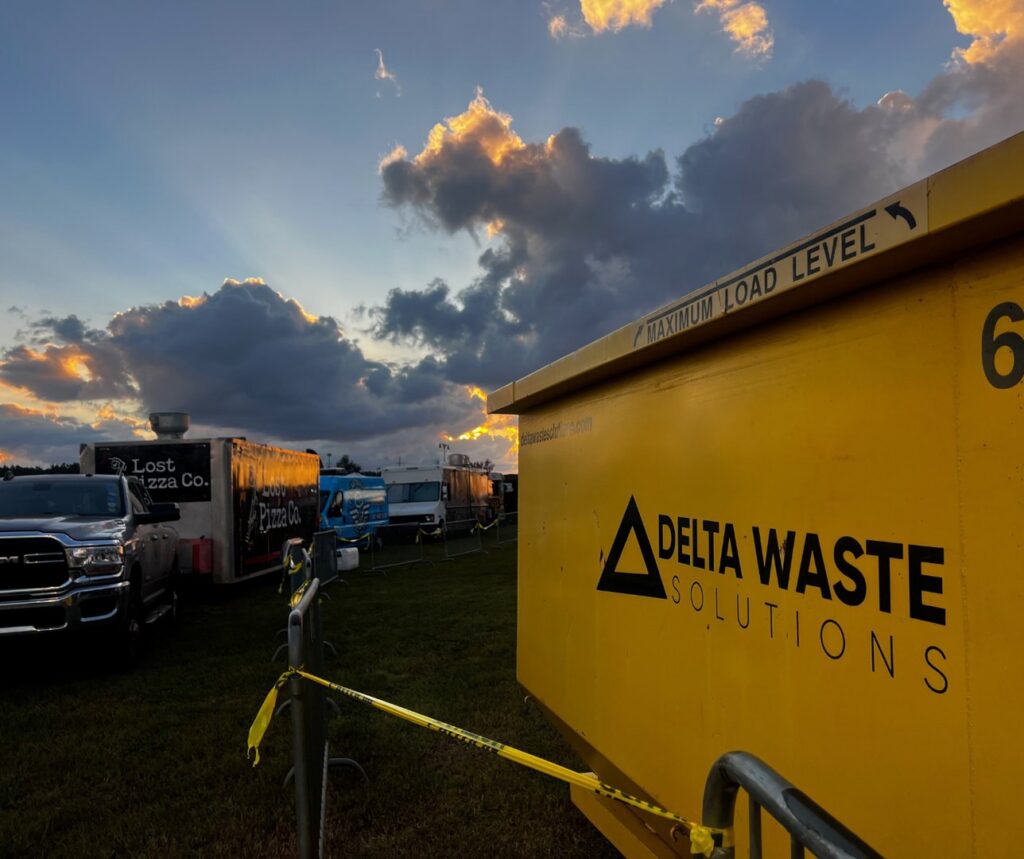 A yellow Delta Waste Solutions dumpster at a food truck event, providing waste solutions and junk removal in Hattiesburg, MS.