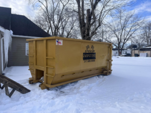 A yellow Speedy Dumpsters roll-off container placed in a snowy residential yard in Brownsburg, IN.