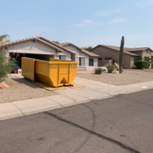 A yellow dumpster placed in a residential driveway for junk removal by AZ Dumpster Rentals in Surprise, AZ