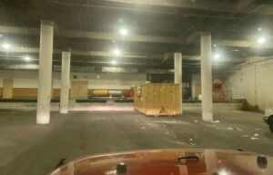 A yellow dumpster positioned in an underground parking garage for commercial junk removal by Massie Dumpster Rental in Las Vegas, NV.