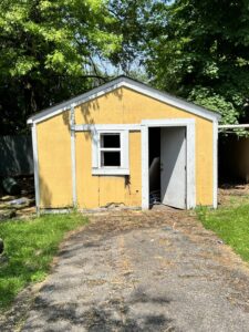 A yellow shed with its door open, revealing items inside that need to be removed by Sos Junk Removal in Akron, OH.