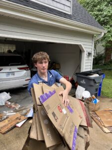 A Young Bucks Junk employee carrying a stack of flattened cardboard boxes for removal in Shawnee, KS.