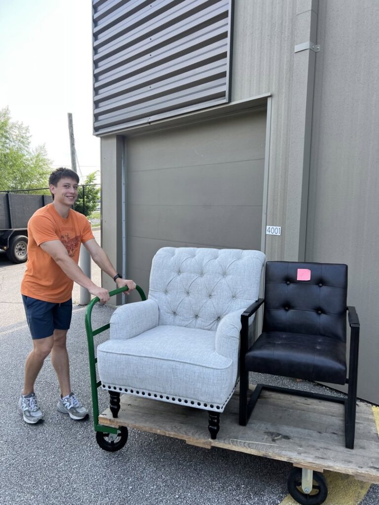 A Young Bucks Junk employee moving two chairs on a dolly outside a commercial building in Shawnee, KS.