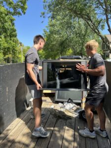 Two Young Bucks Junk employees loading a large window frame onto a trailer for removal in Shawnee, KS.