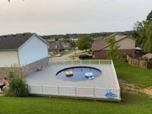An above-ground pool with floats and a surrounding deck in a backyard by Firemaster in Oklahoma City, OK