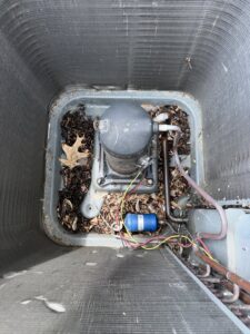 An outdoor AC unit's compressor with leaves and debris, ready for cleaning by Nacho Heating & Cooling Plus Co. in Crest Hill, IL