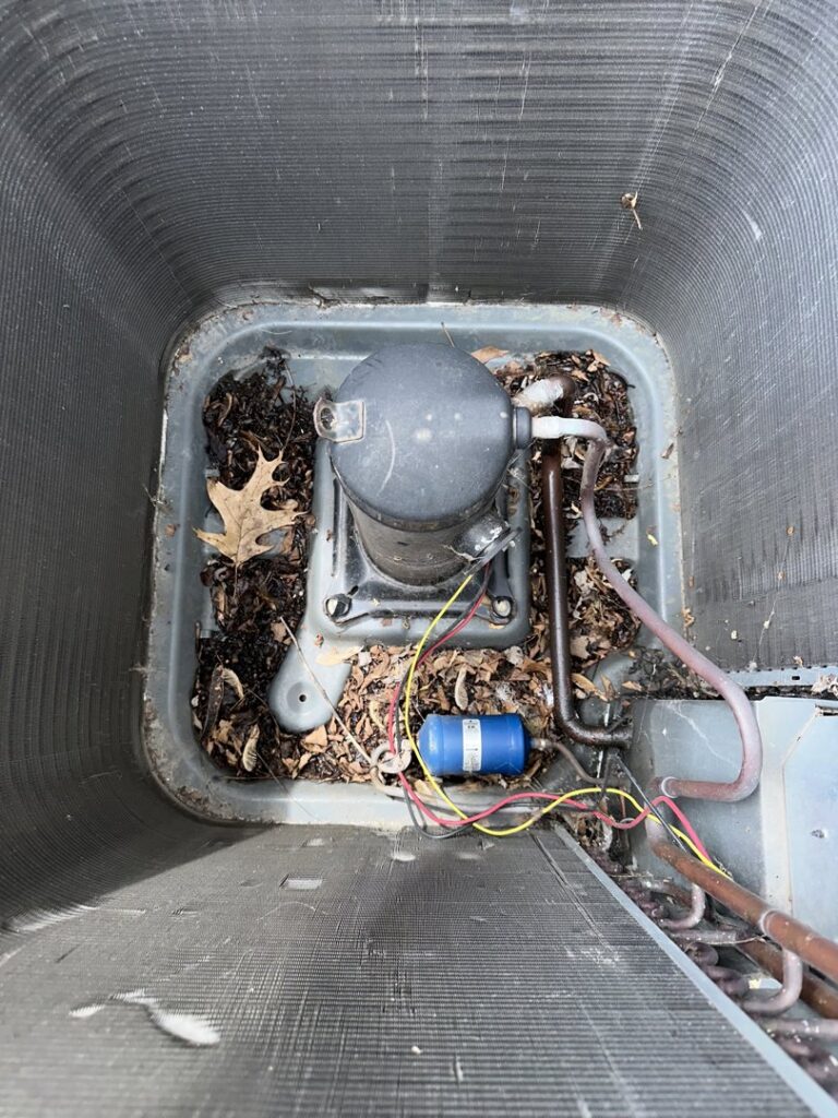 An outdoor AC unit's compressor with leaves and debris, ready for cleaning by Nacho Heating & Cooling Plus Co. in Crest Hill, IL