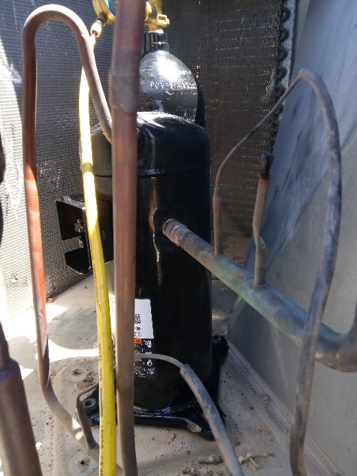An AC compressor with refrigerant lines and gauges attached during service by Ace A/C & Heating in Henderson, NV.