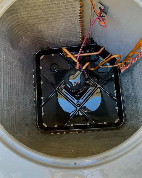 Close-up of an AC condenser coil and drain pan during maintenance by Nevada Heating Reno in Sparks, NV.