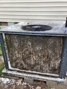 An outdoor AC condenser unit covered in cleaning foam during a maintenance service by Your Angel Heating And Cooling LLC in Cary, NC.