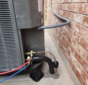 Close-up of an AC condenser unit showing refrigerant lines and electrical connections by Air Factory Heating & Cooling Company in Oklahoma City, OK.
