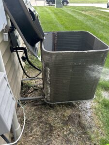 An outdoor AC condenser unit being professionally cleaned by Omega Air Solutions in West Des Moines, IA.