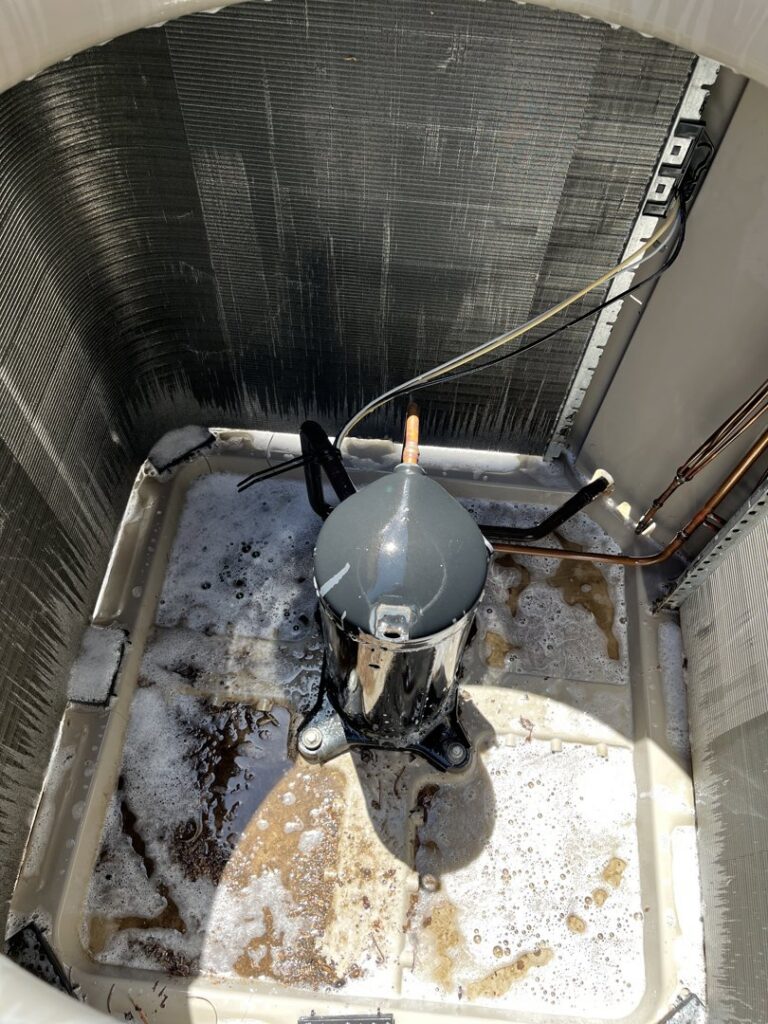 An AC condenser unit being cleaned during maintenance by The Heating & Cooling Company LLC in Las Vegas, NV.
