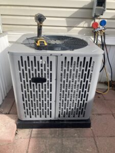 An outdoor AC condenser unit being serviced with refrigerant gauges by LUCAS Heating And Air LLC in Salt Lake City, UT.