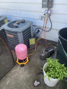 An outdoor AC unit undergoing refrigerant service with gauges and a vacuum pump by Kane Heating & Air in Mountain Top, PA.