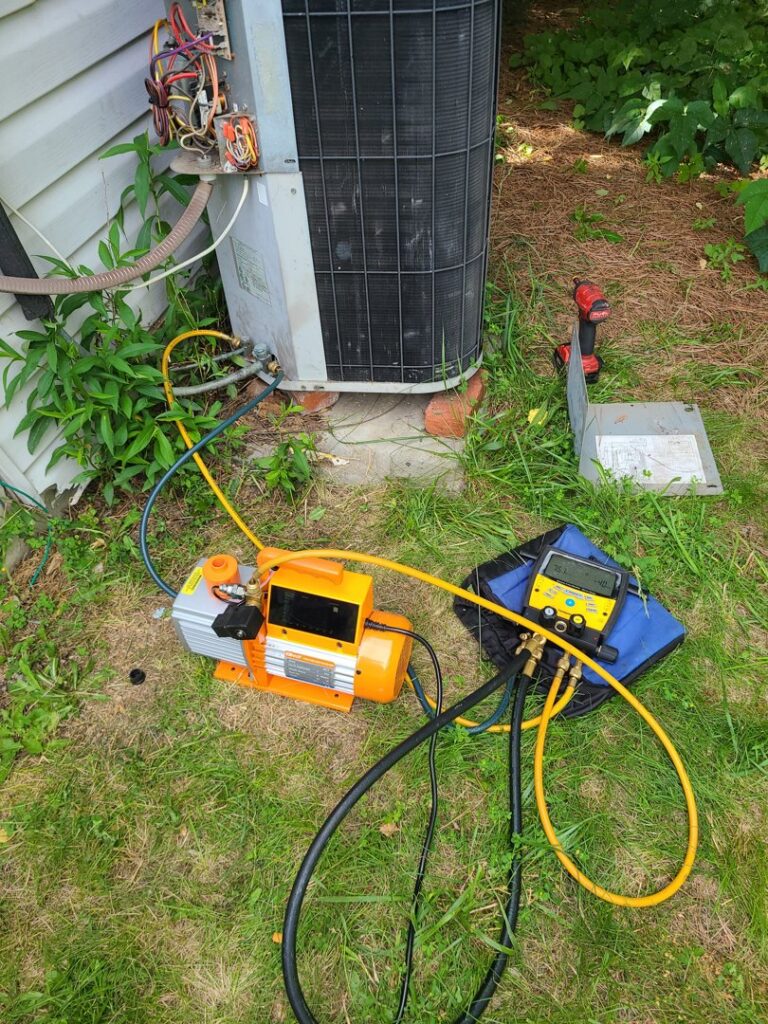 HVAC technician performing refrigerant service with gauges and a vacuum pump on an outdoor AC unit by Duct Pros in Martinsburg, WV