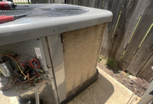 An outdoor AC unit with its side panel removed, showing a dirty coil during an inspection by Noble Heating And Cooling in Wichita, KS.
