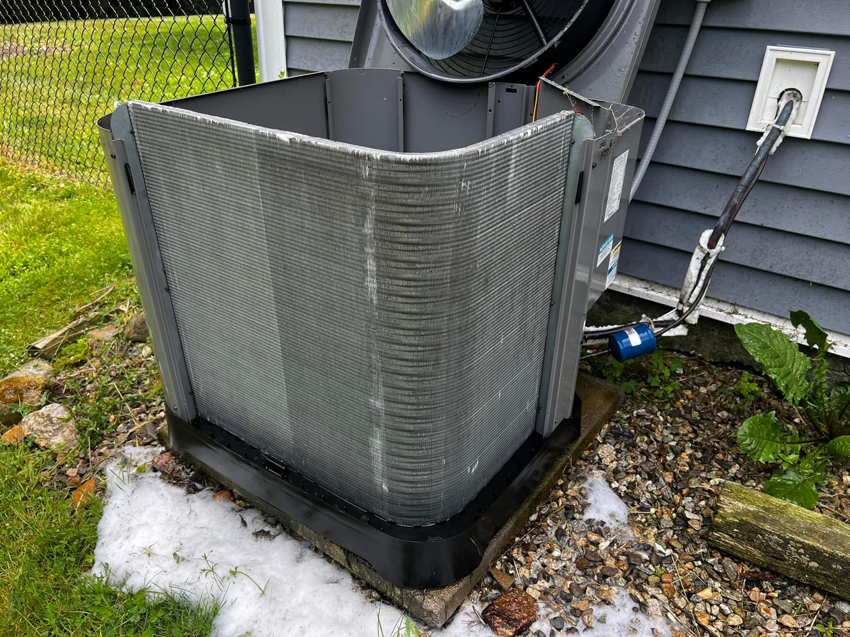 An outdoor air conditioning unit with its top open, showing coils covered in ice or cleaning foam by All Points HVAC in Worcester, MA.