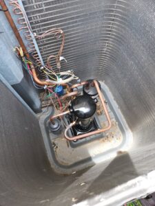 Close-up view of an outdoor AC unit's compressor and coils during an inspection or service by Duct Pros in Martinsburg, WV