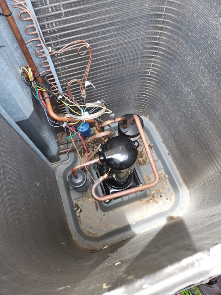 Close-up view of an outdoor AC unit's compressor and coils during an inspection or service by Duct Pros in Martinsburg, WV