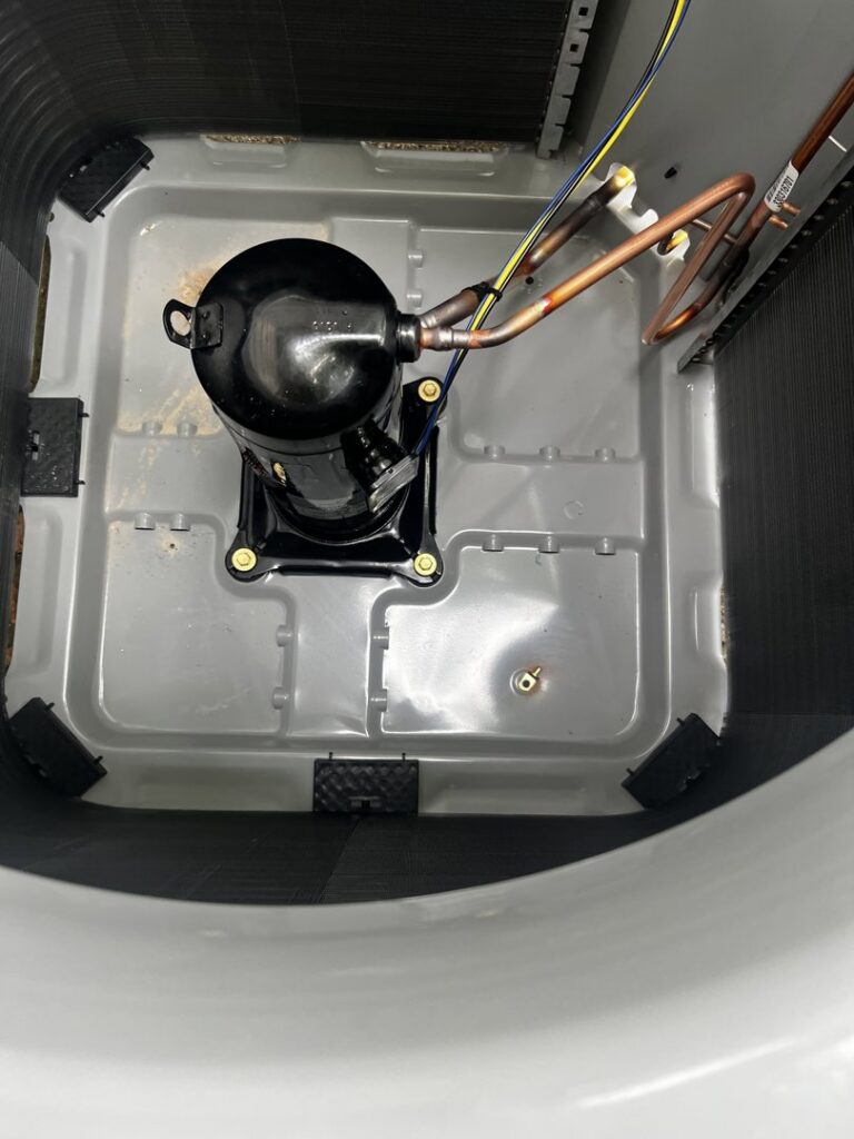 An inside view of an outdoor AC unit showing the compressor, indicating service by All Around Heating & Cooling in Akron, OH.