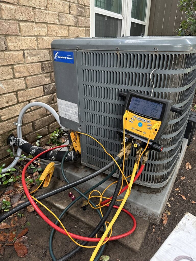 An outdoor Copeland Scroll AC unit undergoing diagnostic testing with manifold gauges by Texas Air & Heat in Arlington, TX.