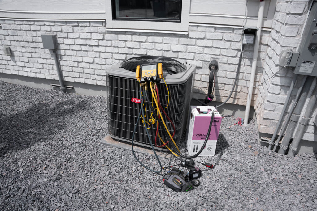 An outdoor AC unit undergoing diagnostic and service with gauges and tools by CSA HVAC Services in Orem, UT.