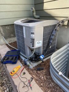 An outdoor air conditioning unit undergoing diagnostic service with tools laid out by Jump HVAC in Lakewood, CO.