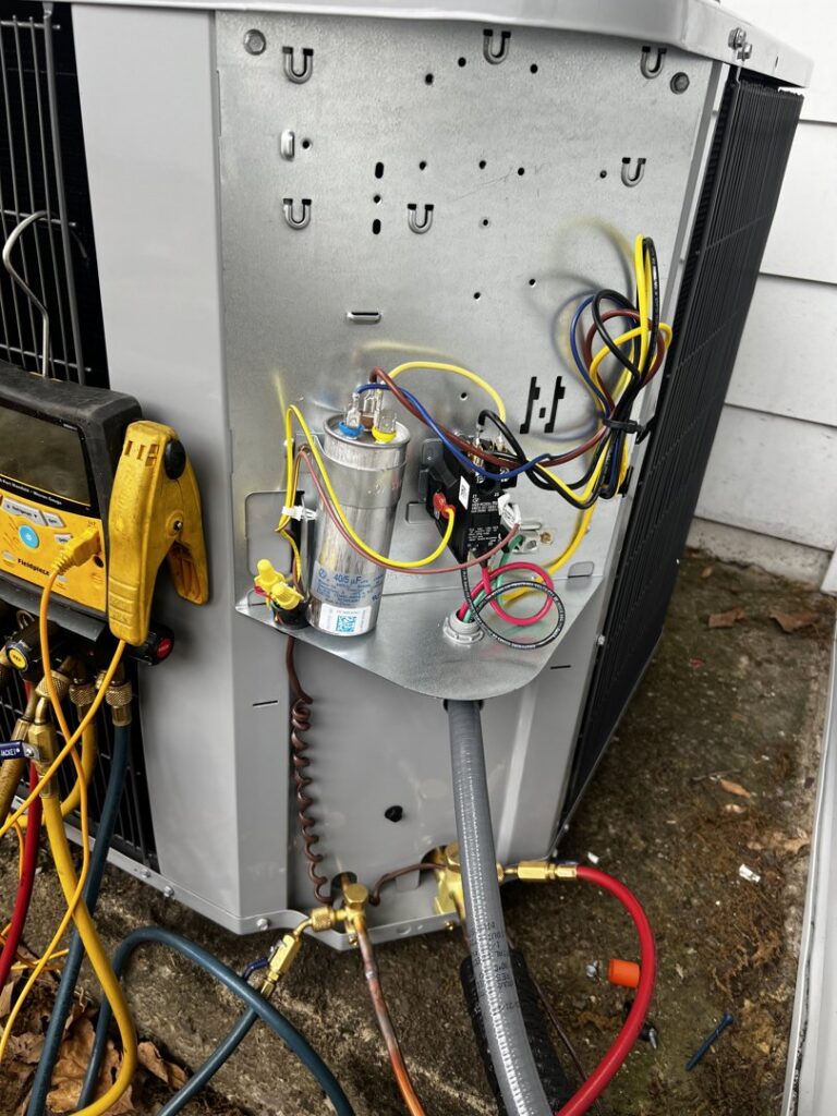 Close-up of an outdoor AC unit's electrical components and refrigerant lines being serviced by All Around Heating & Cooling in Akron, OH.