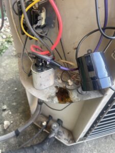 Close-up of electrical components and a refrigerant leak on an outdoor AC unit, serviced by Total HVAC - Heating and Cooling in Nashville, TN.
