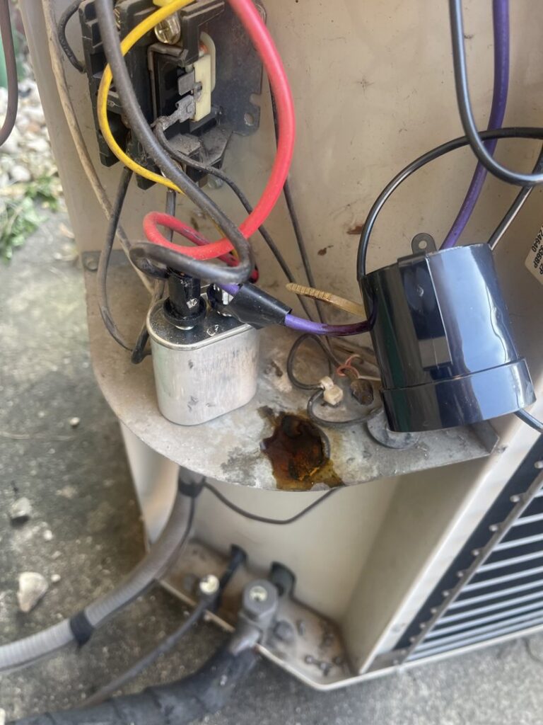 Close-up of electrical components and a refrigerant leak on an outdoor AC unit, serviced by Total HVAC - Heating and Cooling in Nashville, TN.