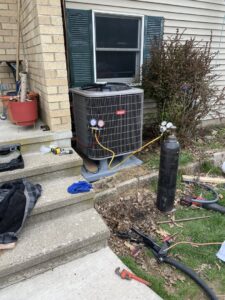 An outdoor AC unit being installed or serviced with gauges and a refrigerant tank by Kane Heating & Air in Mountain Top, PA.