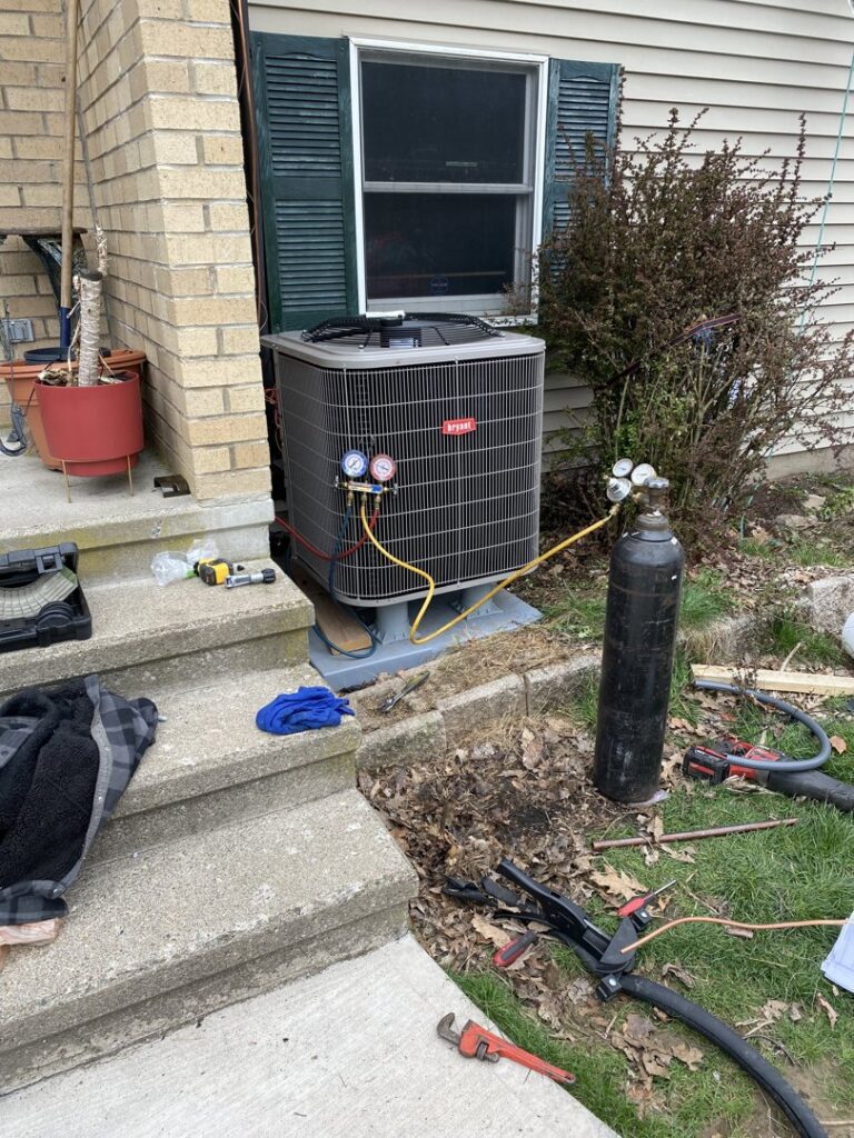 An outdoor AC unit being installed or serviced with gauges and a refrigerant tank by Kane Heating & Air in Mountain Top, PA.