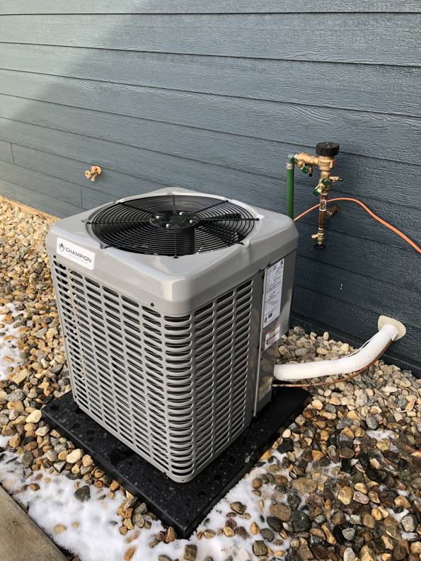 A Champion outdoor AC unit installed on a pad with some snow on the ground by Air Care in Sioux Falls, SD.