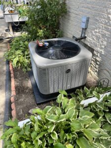 An outdoor air conditioning unit undergoing maintenance with gauges connected by Adam's HVAC in Naperville, IL.