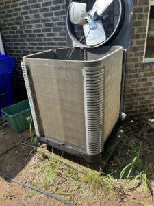 An outdoor AC unit undergoing maintenance with its top fan removed by Oklahoma Climate Solutions in Oklahoma City, OK.